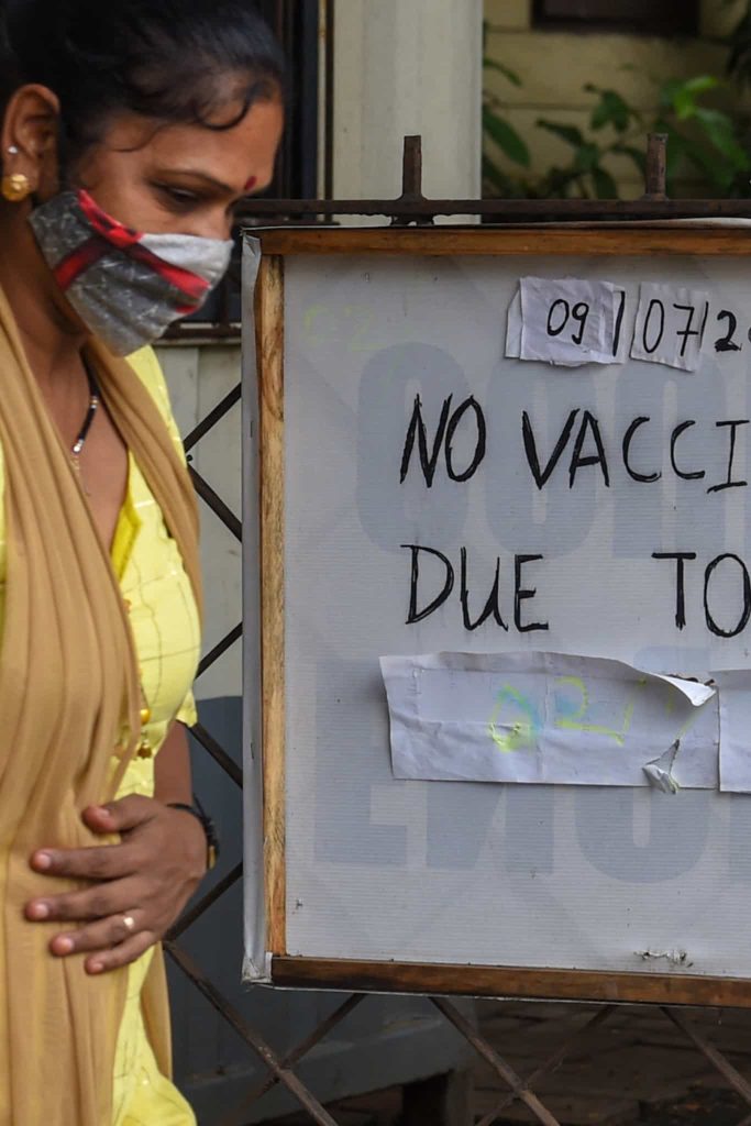 Mulher ao lado de um aviso sobre ausência de vacinas.