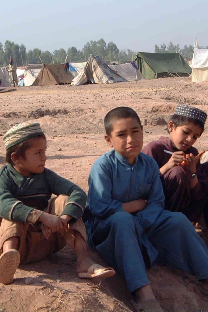Crianças sentadas em um campo de refugiados.