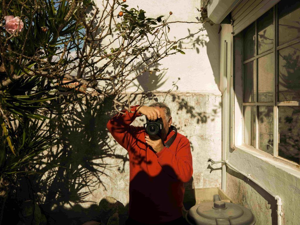 Homem a tirar uma fotografia com uma câmara num ambiente exterior.