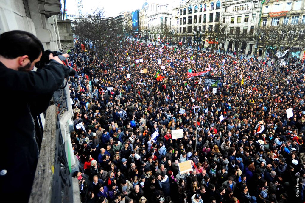 Multidão em protesto com cartazes na rua.