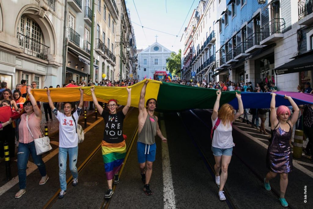 Desfile com bandeira arco-íris em celebração da diversidade.