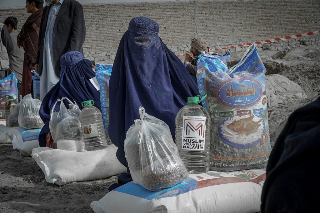 Distribuição de ajuda humanitária para mulheres de burca com arroz e água.