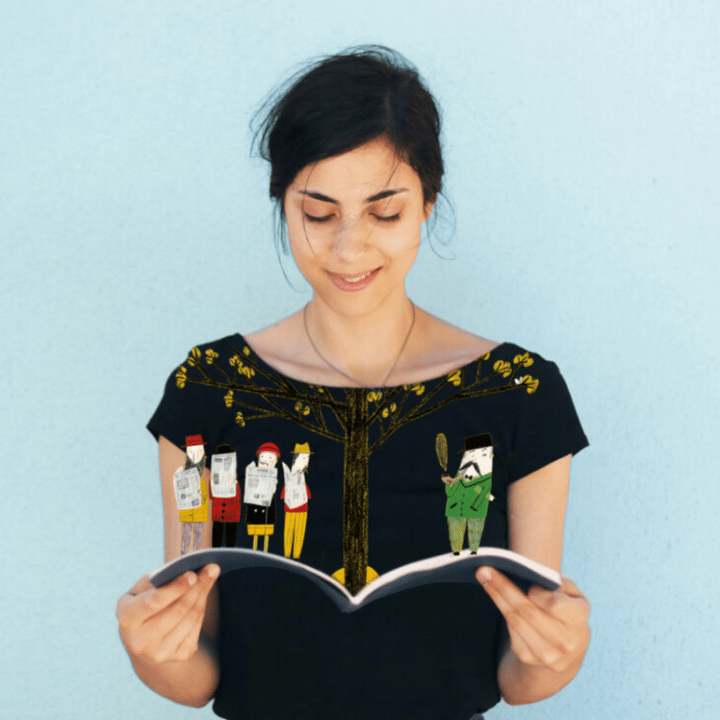 Mulher a ler um livro com ilustrações na camiseta.
