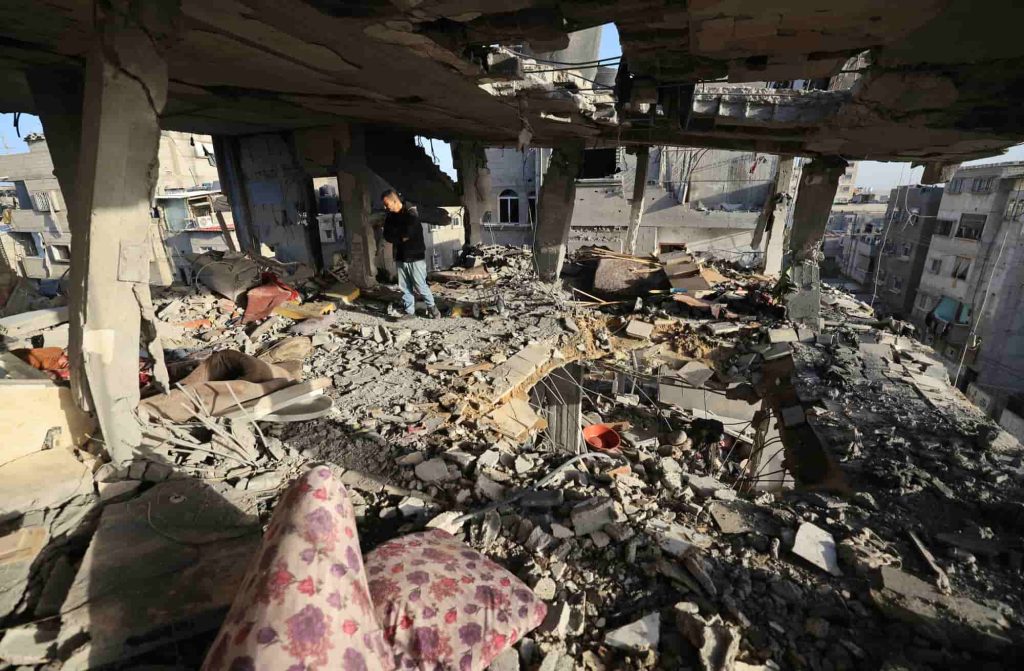 Homens verificam os estragos na casa da família palestiniana Nofal, morta durante o bombardeamento israelita, a 10 de janeiro de 2024, em Rafah, no sul da Faixa de Gaza. Foto da AFP