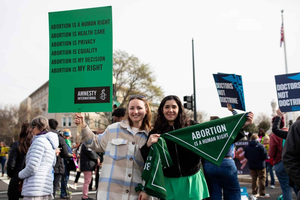 Duas mulheres seguram cartazes onde se lê que o aborto é um direito humano. Apoiantes da Amnistia Internacional dos EUA protestam pelo direito ao aborto junto ao Supremo Tribunal em Washington DC. Foto © Lauren Murphy/Amnistia Internacional EUA