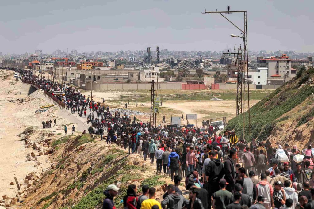 Os palestinianos deslocados tomam a estrada costeira de Rashid para regressar à Cidade de Gaza à passagem por Nuseirat, no centro da Faixa de Gaza, a 14 de abril de 2024, no decurso do conflito em curso no território palestiniano entre Israel e o grupo militante Hamas. Foto de -/AFP via Getty Images