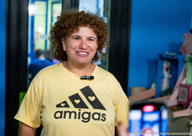 Pierina Nochetti aparece sorridente com uma t-shirt amarela, com o slogan “amigas”, uma brincadeira com o logótipo da Adidas. Foi acusada por ter grafitado uma mensagem, mas as acusações foram entretanto retiradas. Foto © Amnistia Internacional Argentina