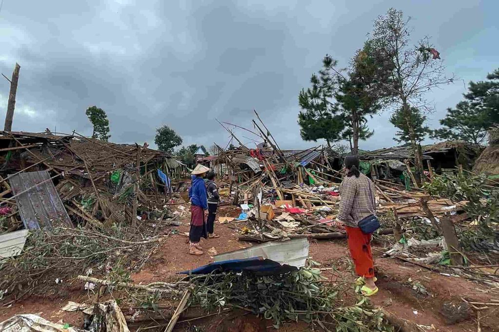 Pessoas junto a abrigos destruídos num campo para deslocados internos após um ataque aéreo perto da cidade de Pekon, no estado de Shan, no sul de Myanmar, a 6 de setembro de 2024. Foto de STR/AFP via Getty Images.