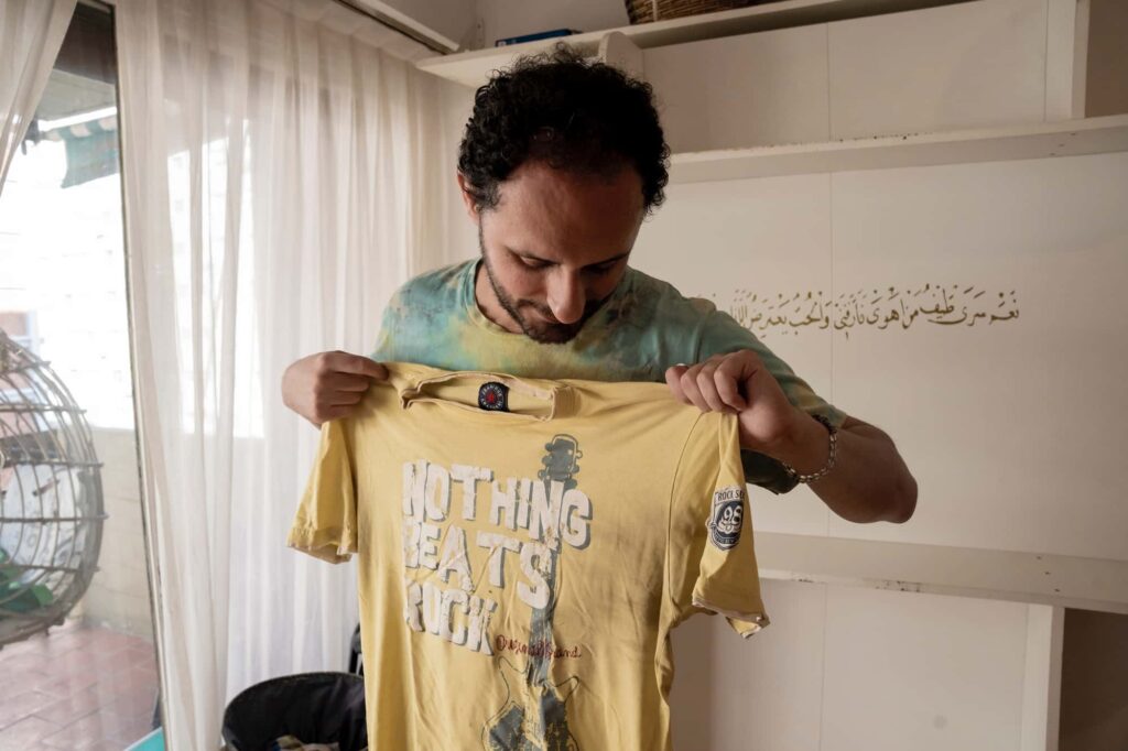 Eyad mostra uma camiseta que a mãe lhe comprou e que o acompanhou muito na Síria nos últimos dias, quando estava a tratar da documentação e a ir aos escritórios do exército em Buenos Aires, Argentina, a 28 de novembro de 2024. Foto © © Anita Pouchard Serra/Amnistia Internacional