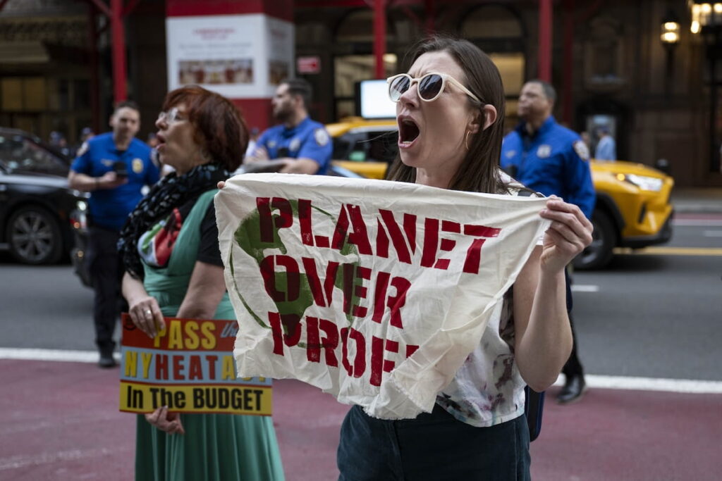 Ativistas climáticos seguram cartazes em frente à residência do bilionário norte-americano Bill Ackman, em Manhattan, durante o protesto "Bye Bye Billionaires Block Party" (Festa de Rua Adeus Bilionários), no Dia da Terra, em Nova Iorque, EUA, a 22 de abril de 2025. (Foto © Mostafa Bassim/Anadolu via Getty Images)